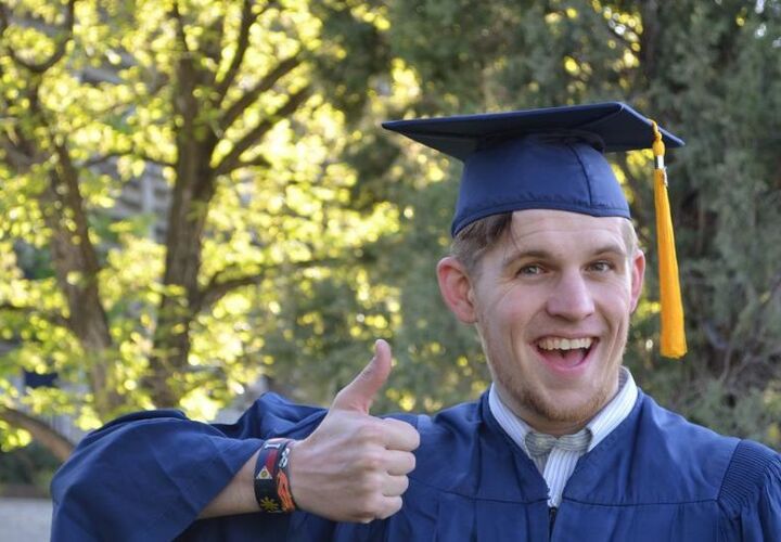 Graduating student holding a thumbs up